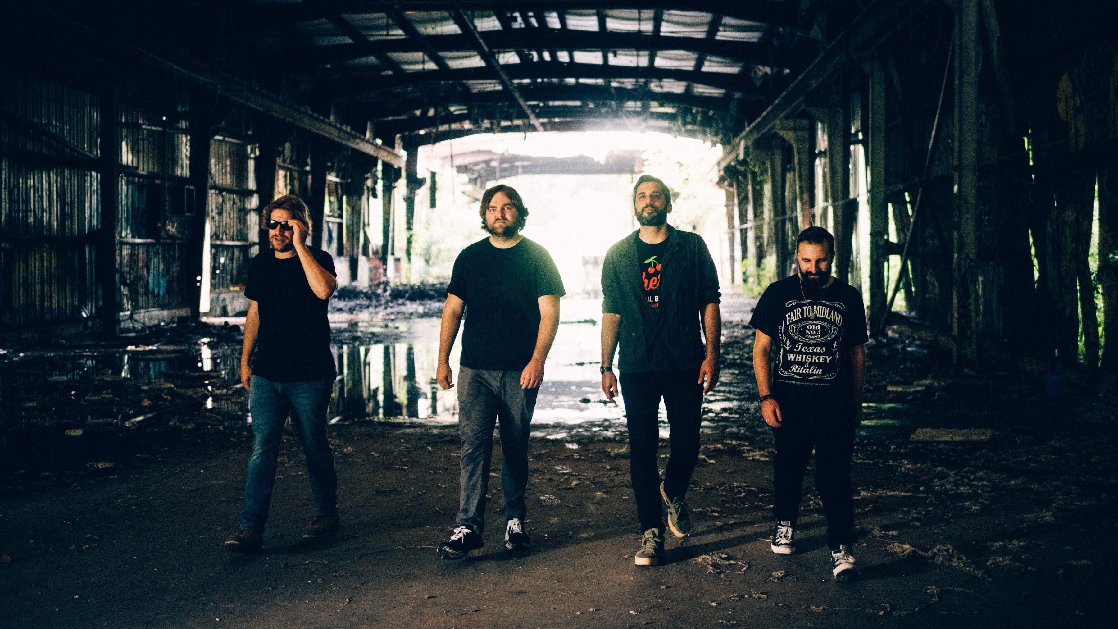 The Rough Edges walking in a dark, dilapidated warehouse.