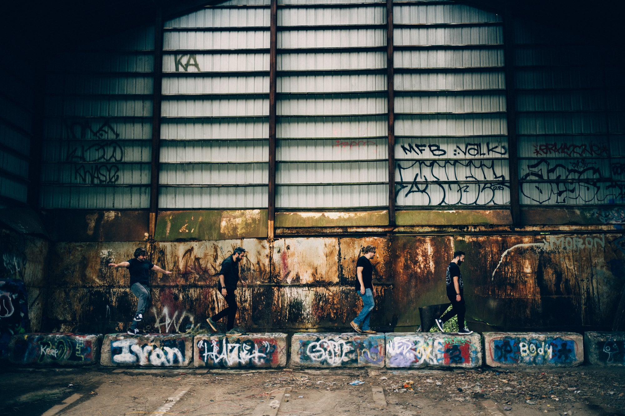 People standing in front of a graffiti-covered wall inside an industrial building.